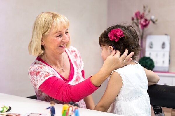Hörakustikerin passt einem Mädchen mit Hörgerät im Fachgeschäft das Hörsystem an.